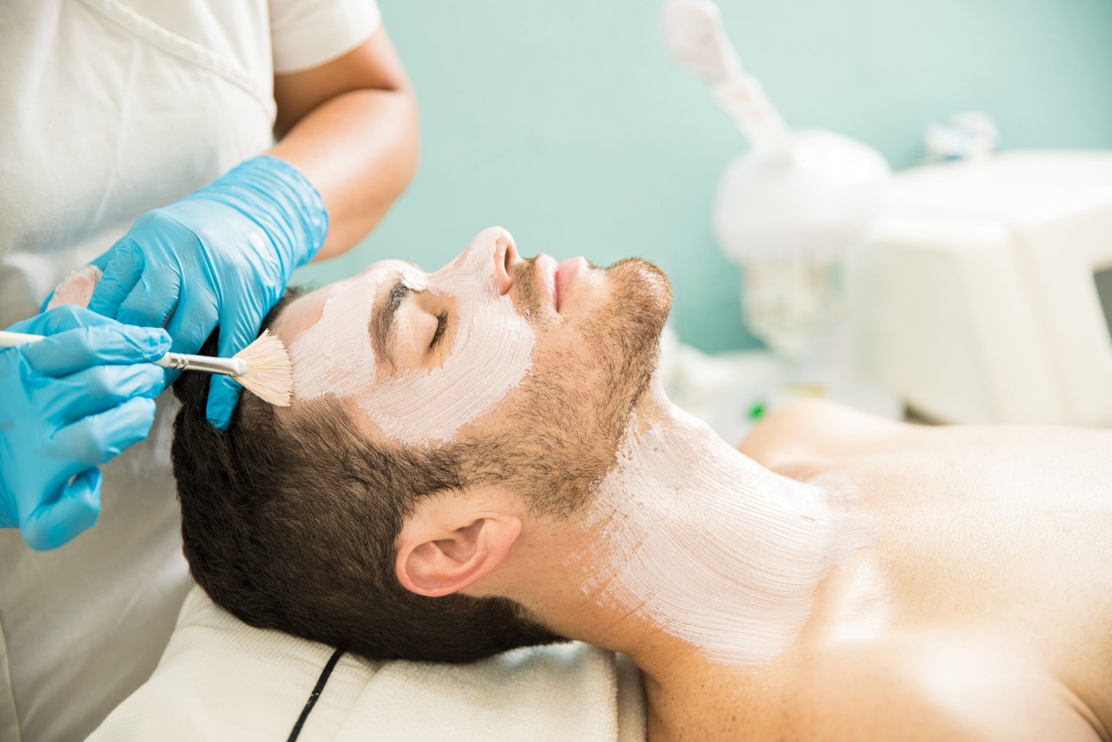 Profile view of a young man getting a moisturizing facial treatment in a health spa